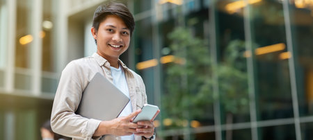 Young asian man entrepreneur with laptop in hand using smartphone