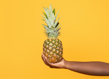Cropped shot of black young man holding pineapple in handの写真素材