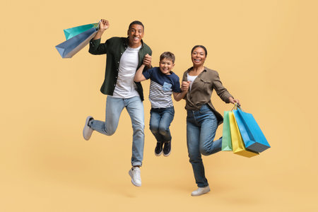Overjoyed african american family jumping with purchasesの写真素材