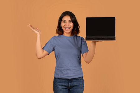 Positive young arab woman holding computer with empty screen