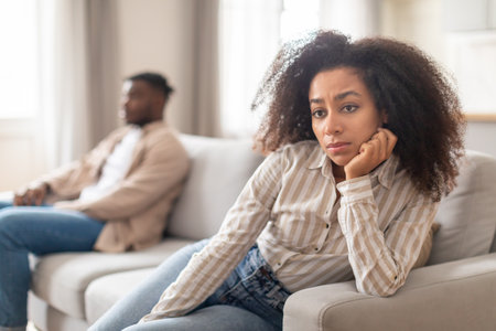Unhappy young black couple experiencing marriage crisis at homeの写真素材