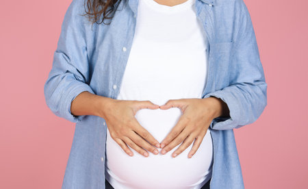 Cropped of expecting young woman holding hands on tummyの写真素材