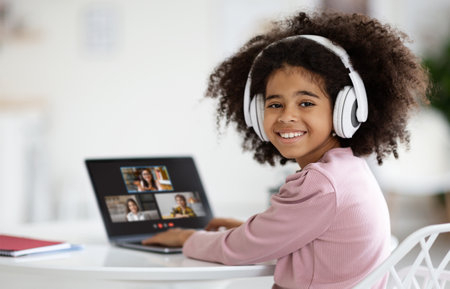 Cute little african american girl attending online lesson from home