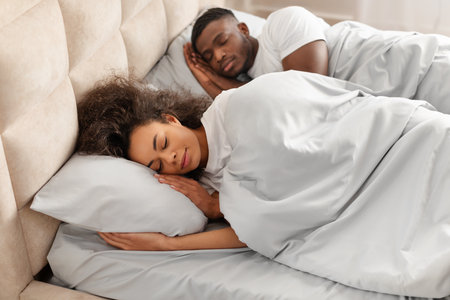 Young black married couple sleeping calmly together lying in bedroomの写真素材