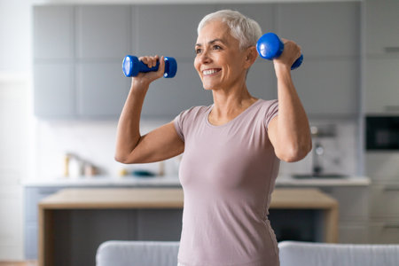 Active European senior lady stays fit exercising with dumbbells indoorの写真素材