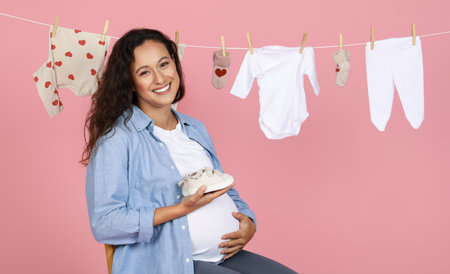 Smiling expecting woman with baby shoe, clotheslineの写真素材