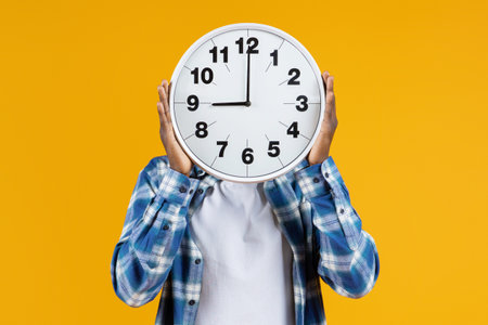 Unrecognizable black male holding large round clock in front of his faceの写真素材