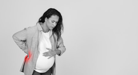 Pregnant Woman Having Back Pain Standing In Studio