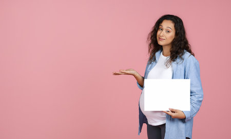 Beautiful smiling pregnant woman with blank white paperの写真素材