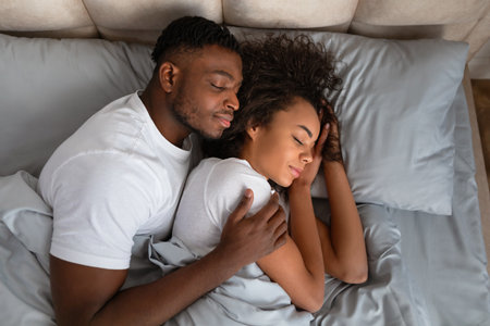 Top view of african american couple sleeping in bed embracingの写真素材