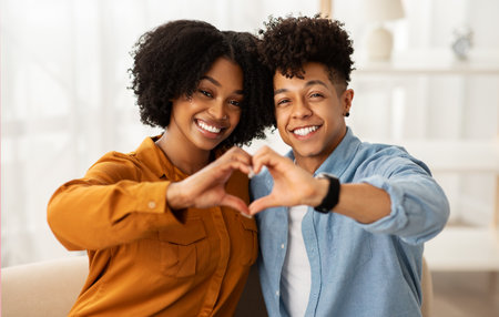 Cheerful young african american woman and man making heart gesture with hands