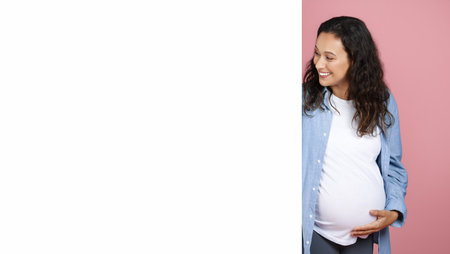 Smiling expecting lady looking at white advertising board