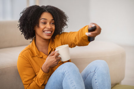 Smiling young african american woman enjoy cup of coffee in handsの写真素材
