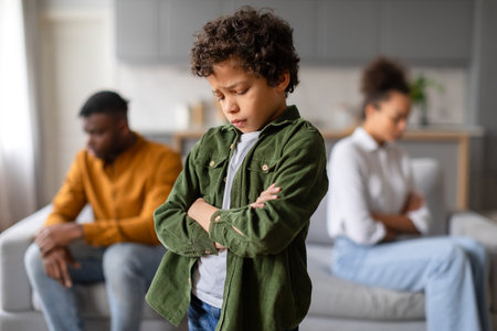 Upset child with arms crossed, parents in backgroundの写真素材