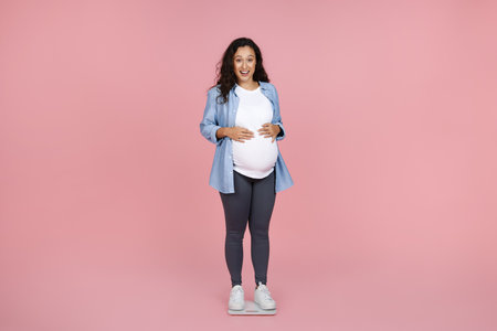 Young woman measuring her pregnant weight standing on scalesの写真素材
