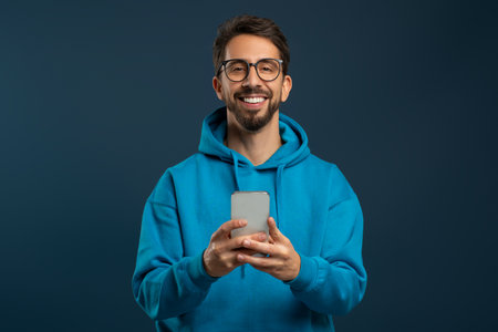 Portrait Of Smiling Handsome Young Man With Smartphone In Handsの写真素材