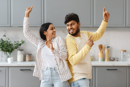 Cheerful young indian man and woman have fun at kitchenの写真素材