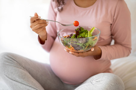 Cropped Shot Of Black Pregnant Lady Eacting Fresh Vegetable Salad At Homeの写真素材