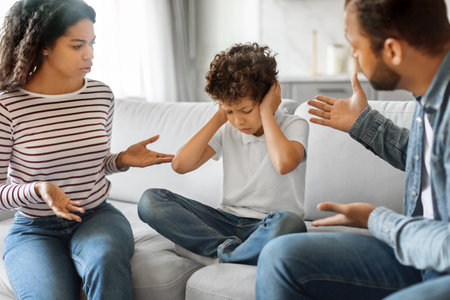 Preteen boy covering ears to block out sound of his parents scoldingの写真素材