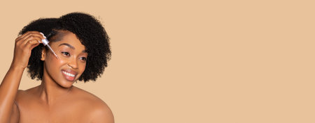 Black woman applying serum for glowing skin careの写真素材