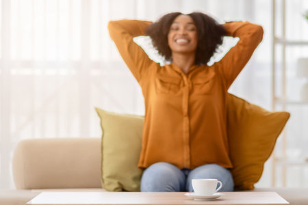 An exuberant young woman with curly hair stretches with her hands behind her headの写真素材