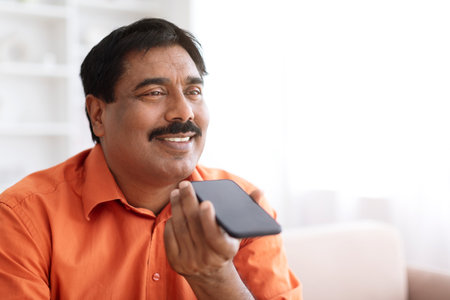 Mature indian man recording voice message, using smartphoneの写真素材