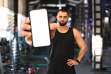 Fitness App. Sporty Man Showing Smartphone With Blank White Screen At Camera