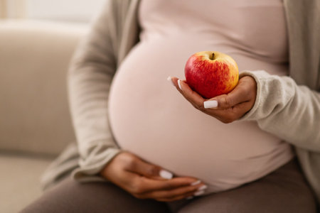 Cropped of african american expecting woman holding apple
