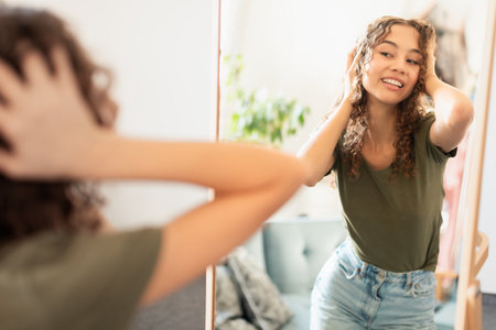 Happy confident teenage lady enjoying reflection in mirror at homeの写真素材