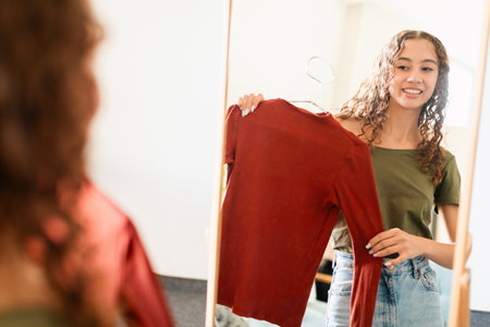 Happy stylish young lady selects perfect outfit in home closetの写真素材