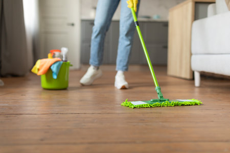 Mopping hardwood floor with cleaning supplies nearbyの写真素材