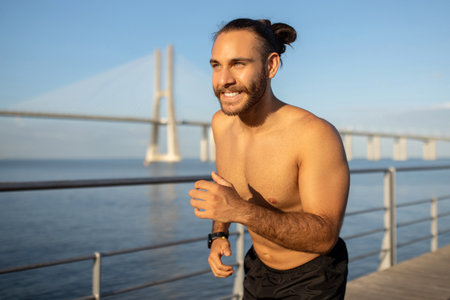 Sporty shirtless guy enjoys outdoor jogging by the seaside