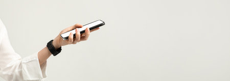 Close-up of a hand holding a smartphone with a white screen, featuring a woman in a white blouseの写真素材