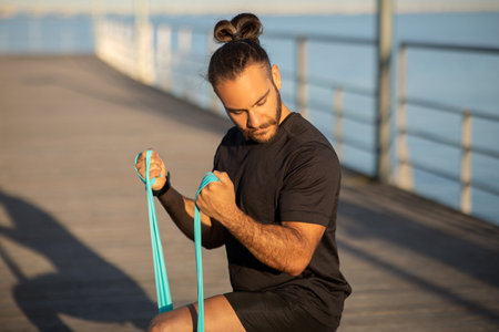 guy in fitness attire exercising with resistance rubber band outdoor