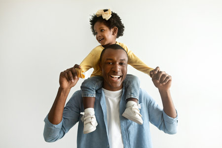 Cute little african american baby girl sitting on father neckの写真素材