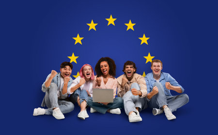 Ecstatic young group sitting with a laptop, celebrating success with raised fistsの写真素材