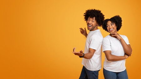 Positive millennial african american couple posing on orangeの写真素材
