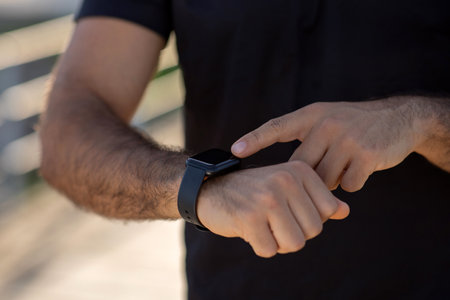 mans hands using smartwatch fitness tracker during workout outside, closeup