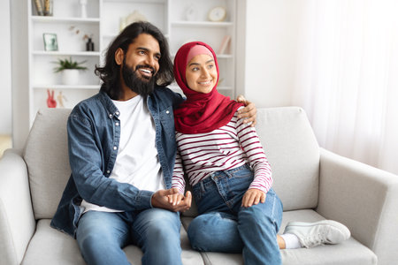 Romantic happy muslim couple relaxing on couch at home