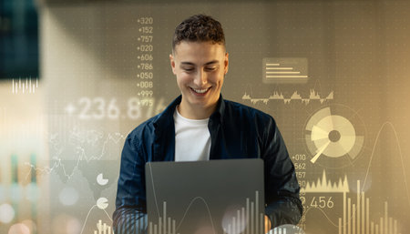 Cheerful young man with a pleasant smile working on a laptop, digital financial analyticsの写真素材