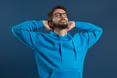 Content young man in glasses reclining with hands behind headの写真素材