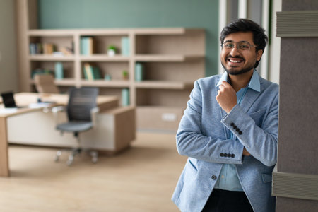 Happy successful Middle Eastern businessman standing in modern office interior