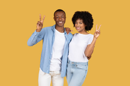 A cheerful young couple wearing casual clothes making peace signs