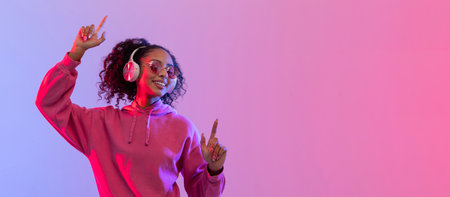 Woman in pink with headphones dancing under neon, free spaceの写真素材