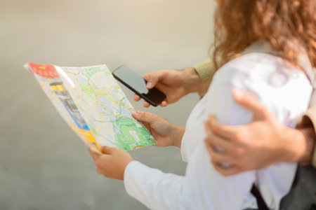 Closeup of tourist couple holding colorful city map and smartphoneの写真素材