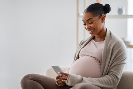 Positive young black pregnant woman using cell phone