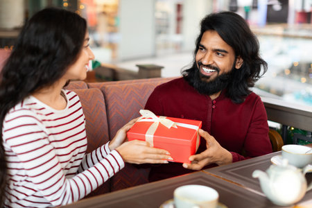 Happy eastern couple celebrating birthday or anniversary at coffee shopの写真素材