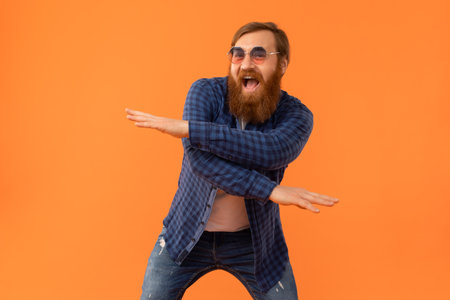 Positive redhaired man with beard dancing making funny moves, studioの写真素材