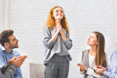 Happy young woman talking in front of group during psychotherapy sessionの写真素材
