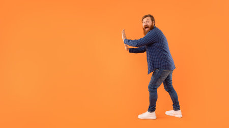 Man With Red Hair And Beard Pushing Invisible Wall, Studioの写真素材